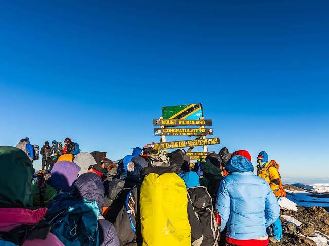 Climbers gathered at the summit sign on Mount Kilimanjaro