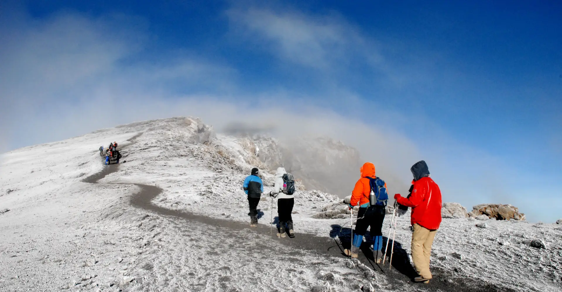 Trekkers ascending a snow-covered volcanic ridge on Mount Kilimanjaro