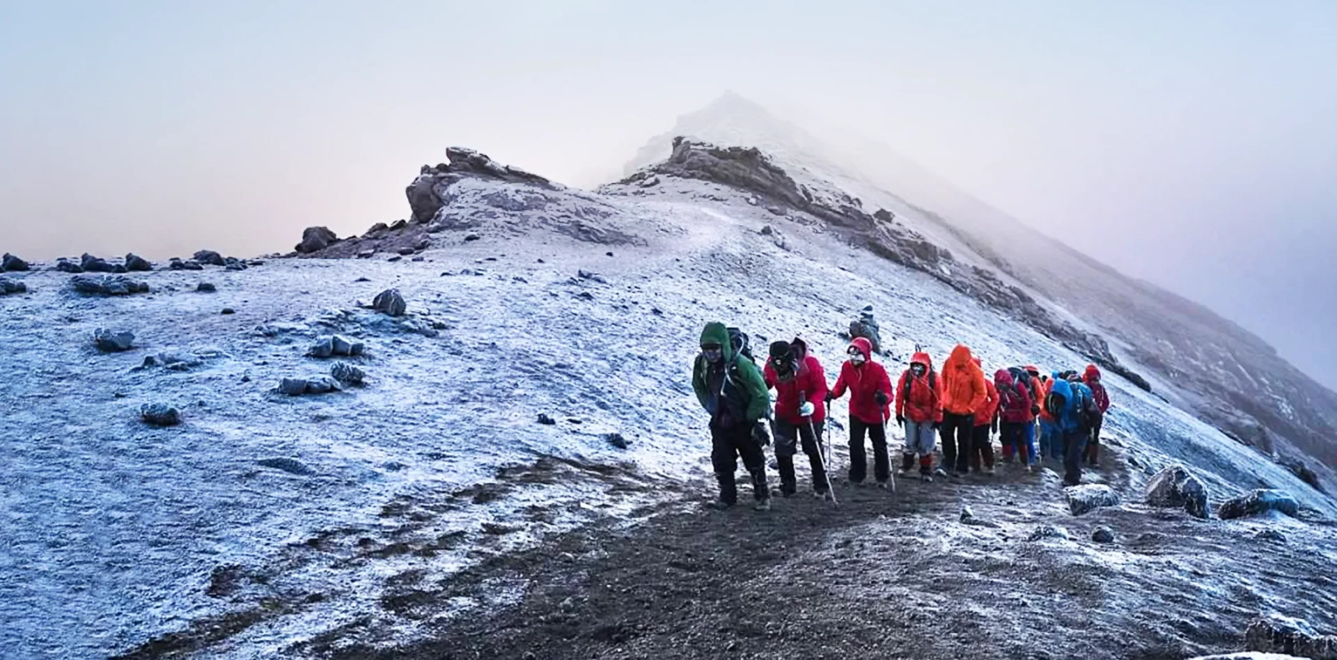 A climbing team ascending snowy upper slopes on Mount Kilimanjaro