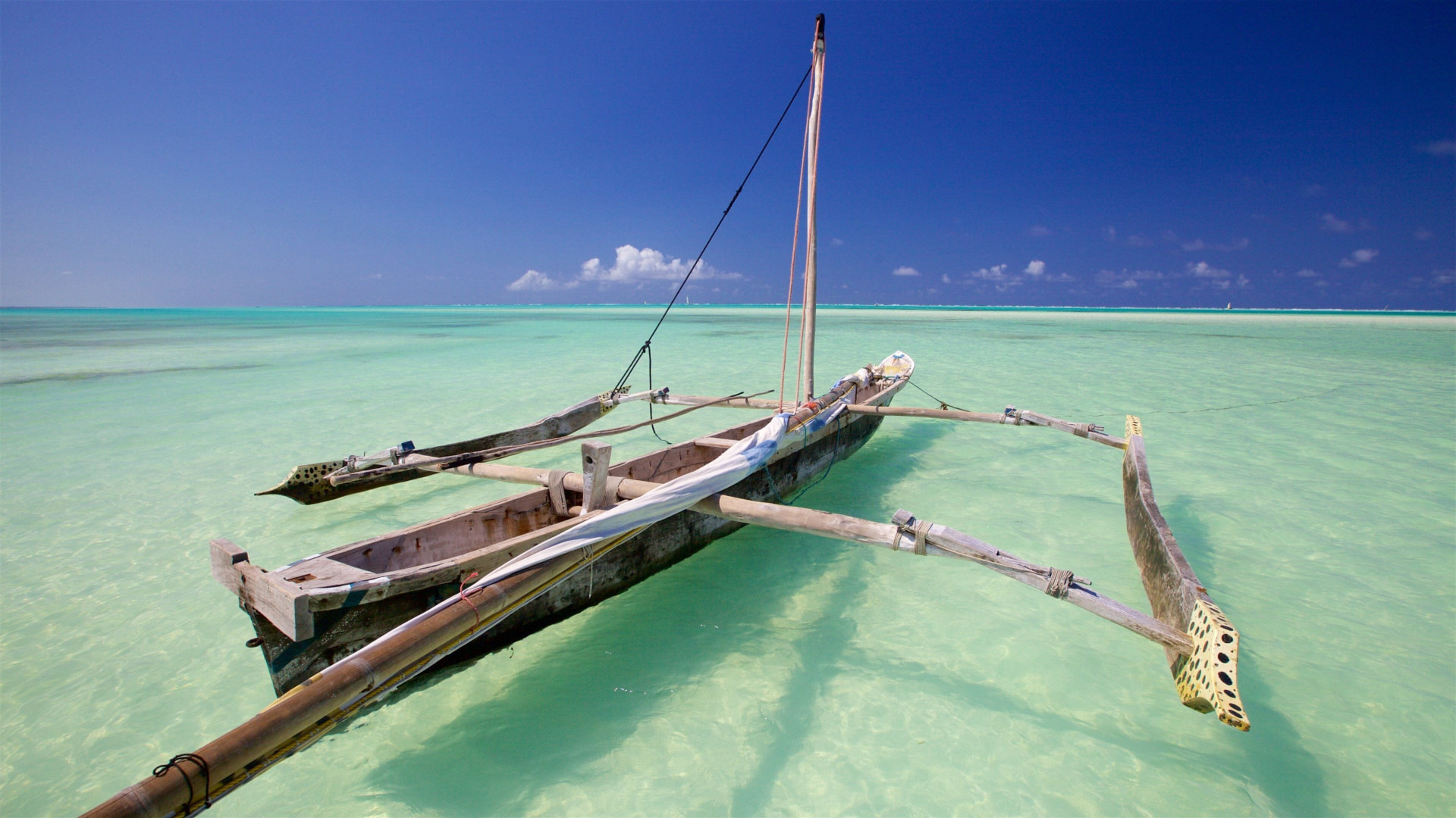 Traditional outrigger boat in shallow turquoise water off Zanzibar