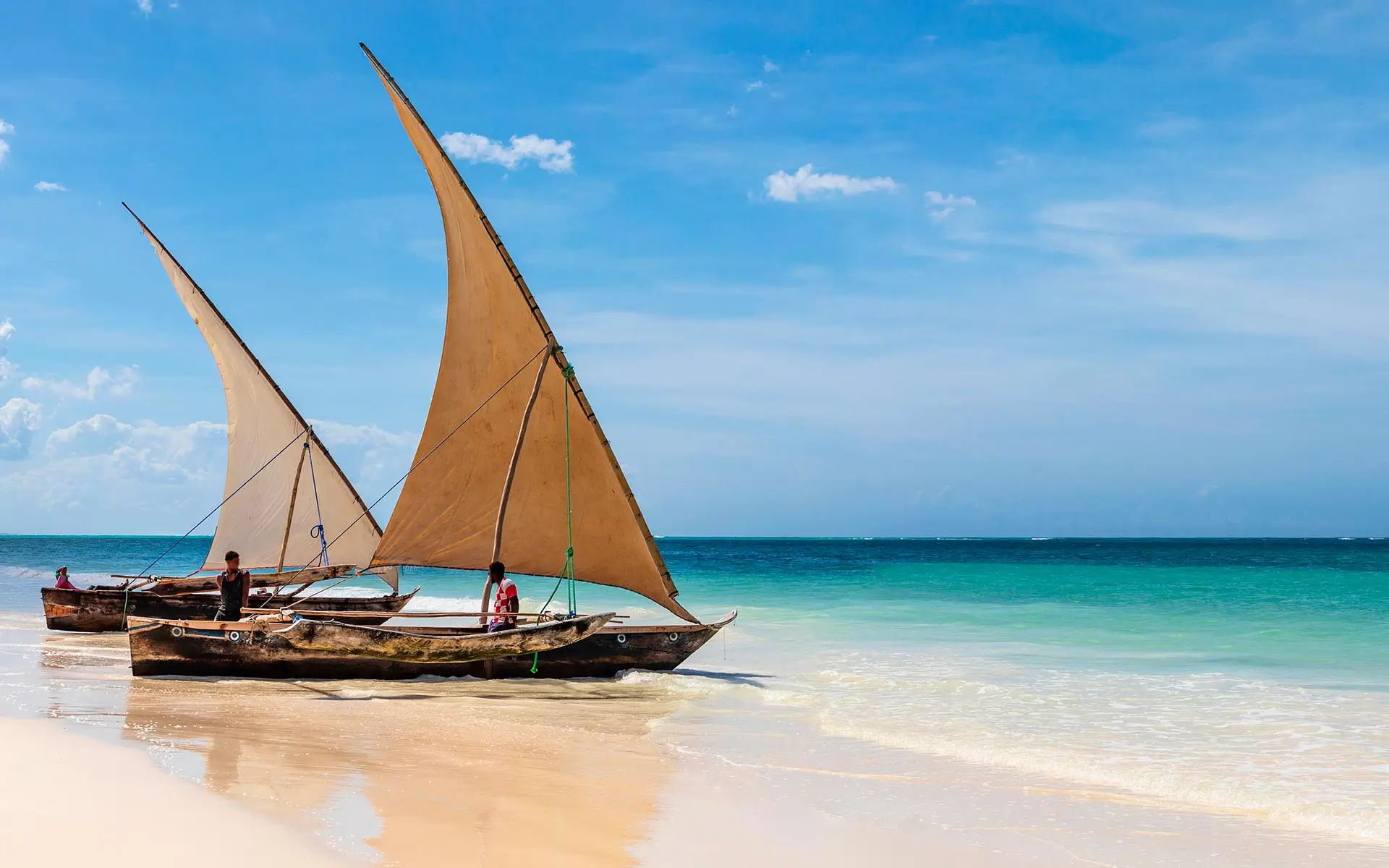 Traditional wooden sailing dhows resting on a Zanzibar beach